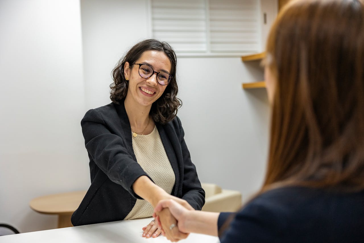 about-02 Businesswomen shaking hands in an office, representing a successful job interview or partnership.