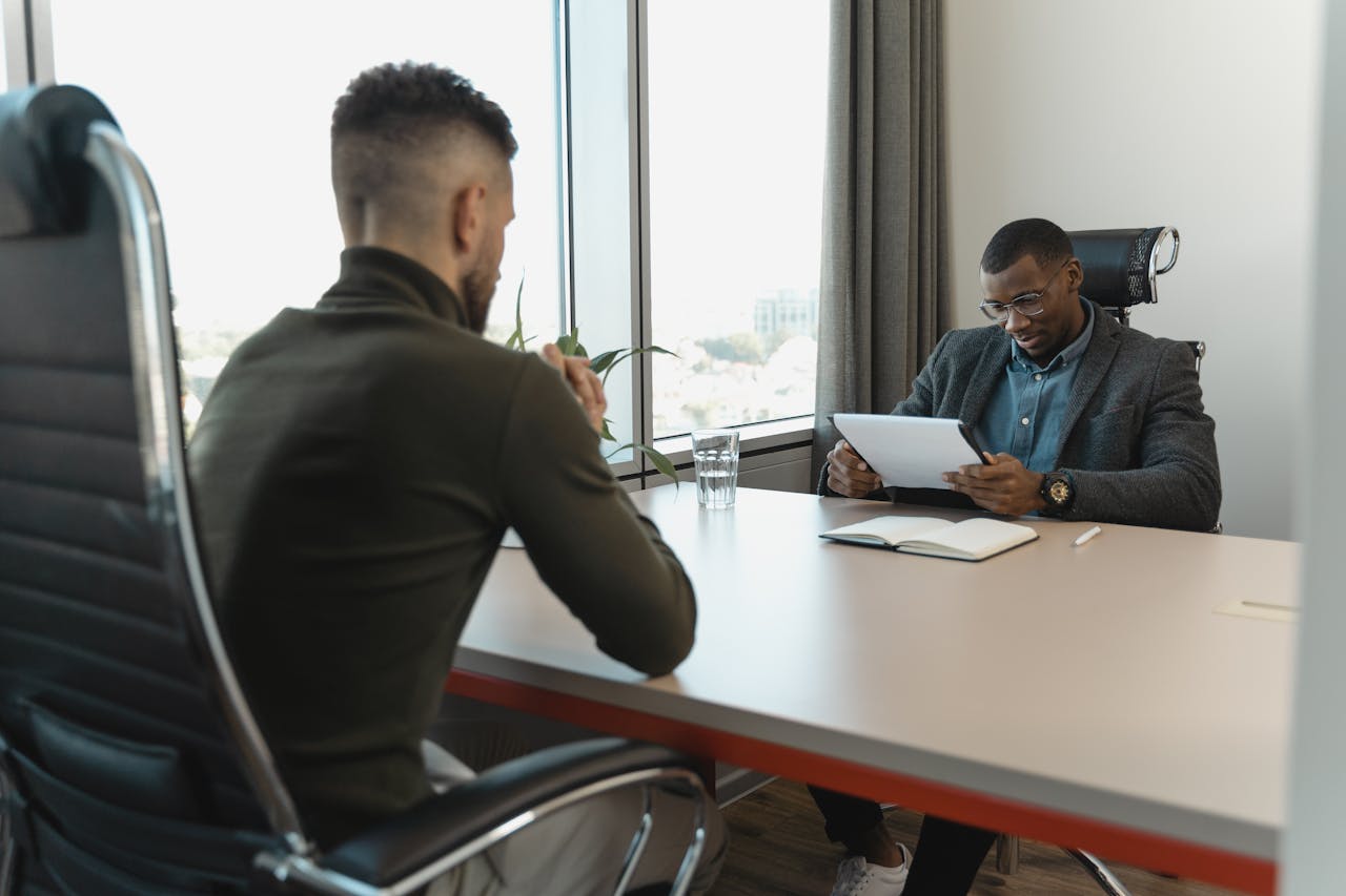 ours-journey A job interview taking place in a modern office setting between two professional men.